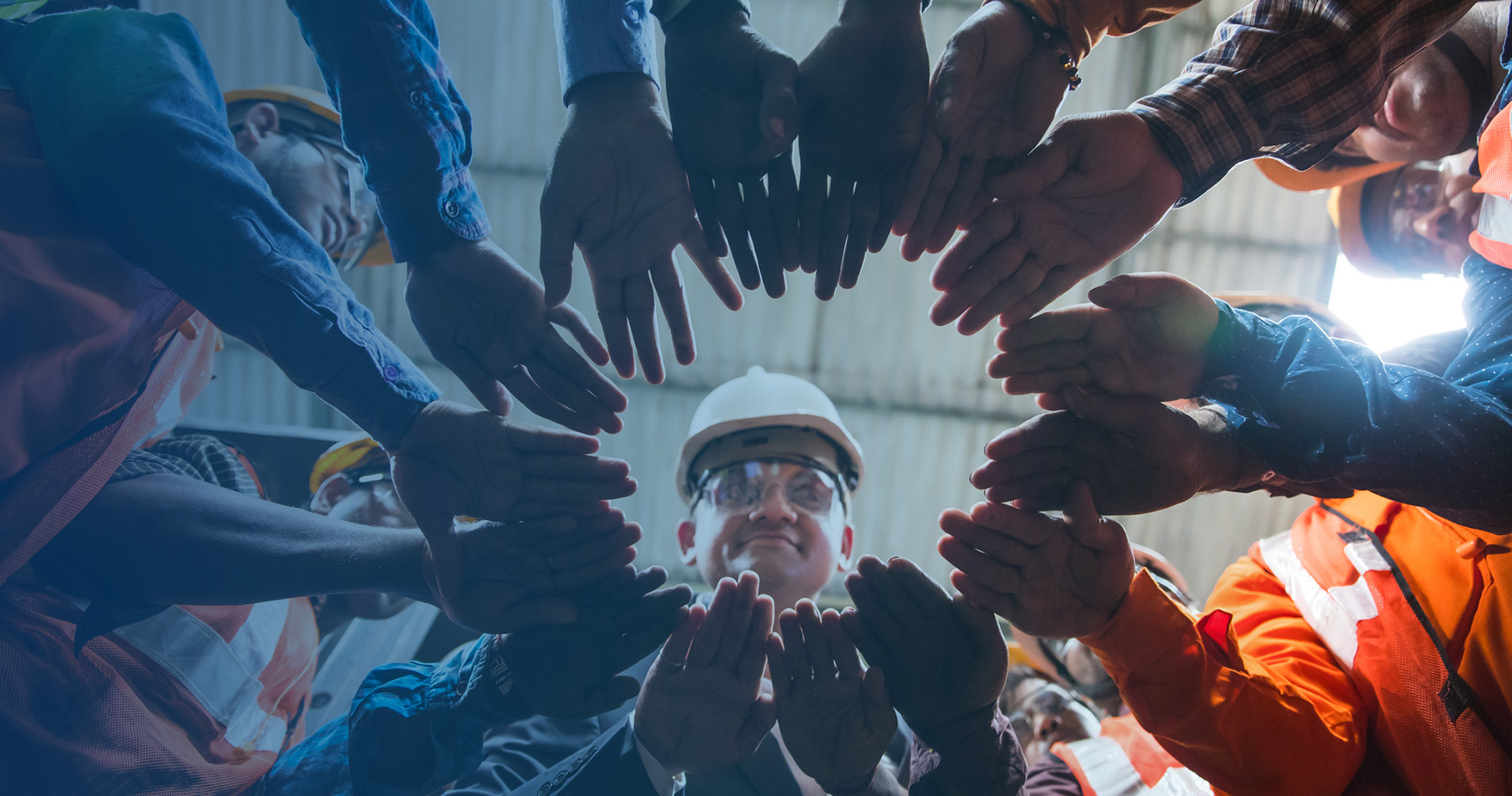 factory workers put their hands in a circle